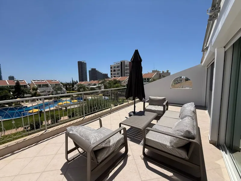 Private 30 m² balcony with lounge furniture overlooking the pool and Limassol skyline