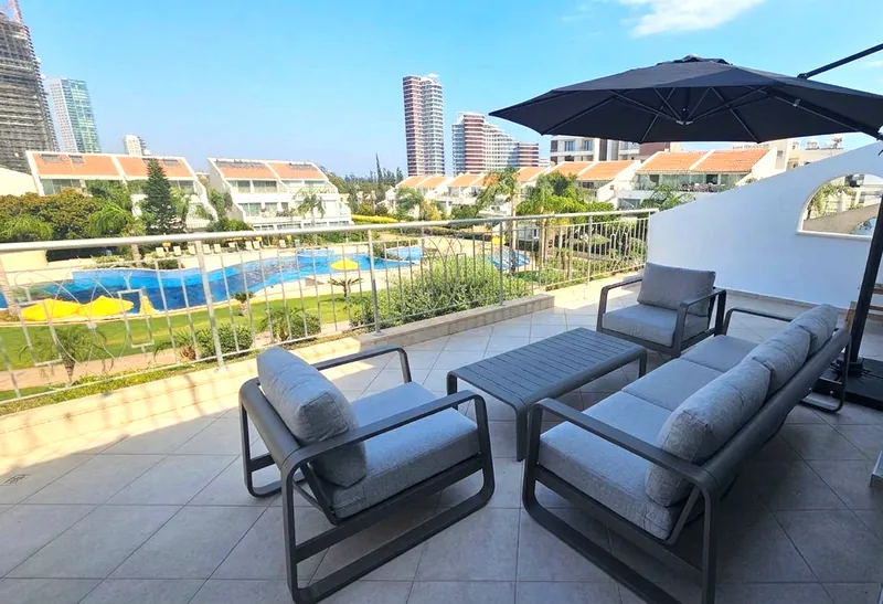 Balcony with lounge sofa, armchairs and parasol overlooking the pool